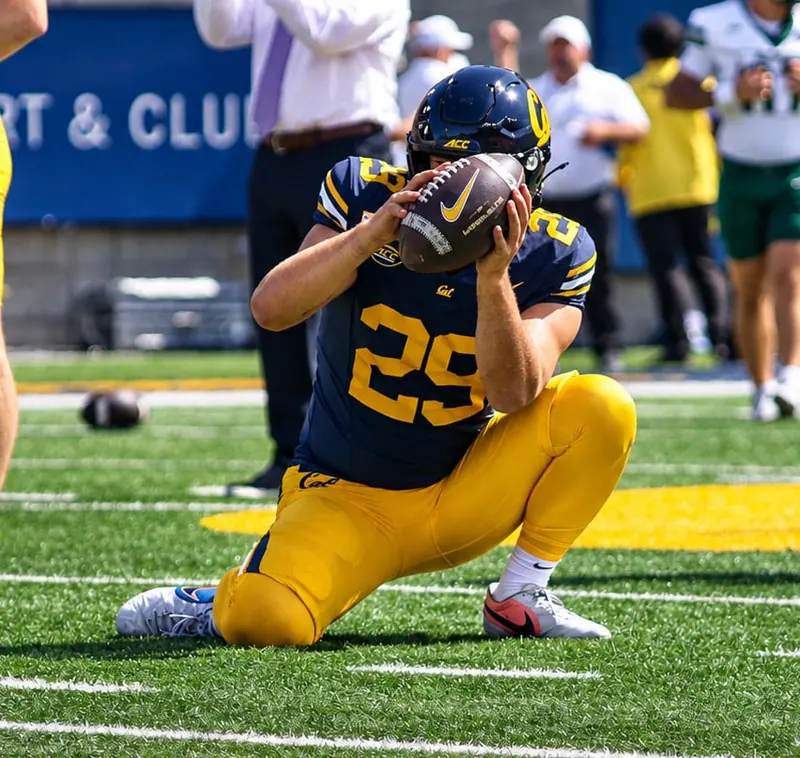 Cal Golden Bears number 29 kneeling on the field holding a football